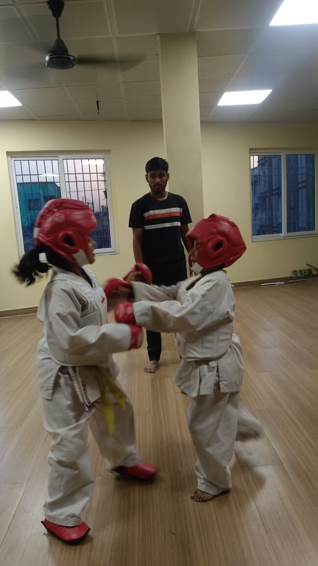 Coach supervising two young Karate students during a sparring drill at Sports Zone LLP, Patna