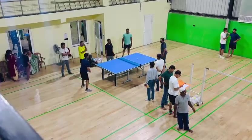 Aerial video of doubles Badminton being played during a tournament, with spectators courtside